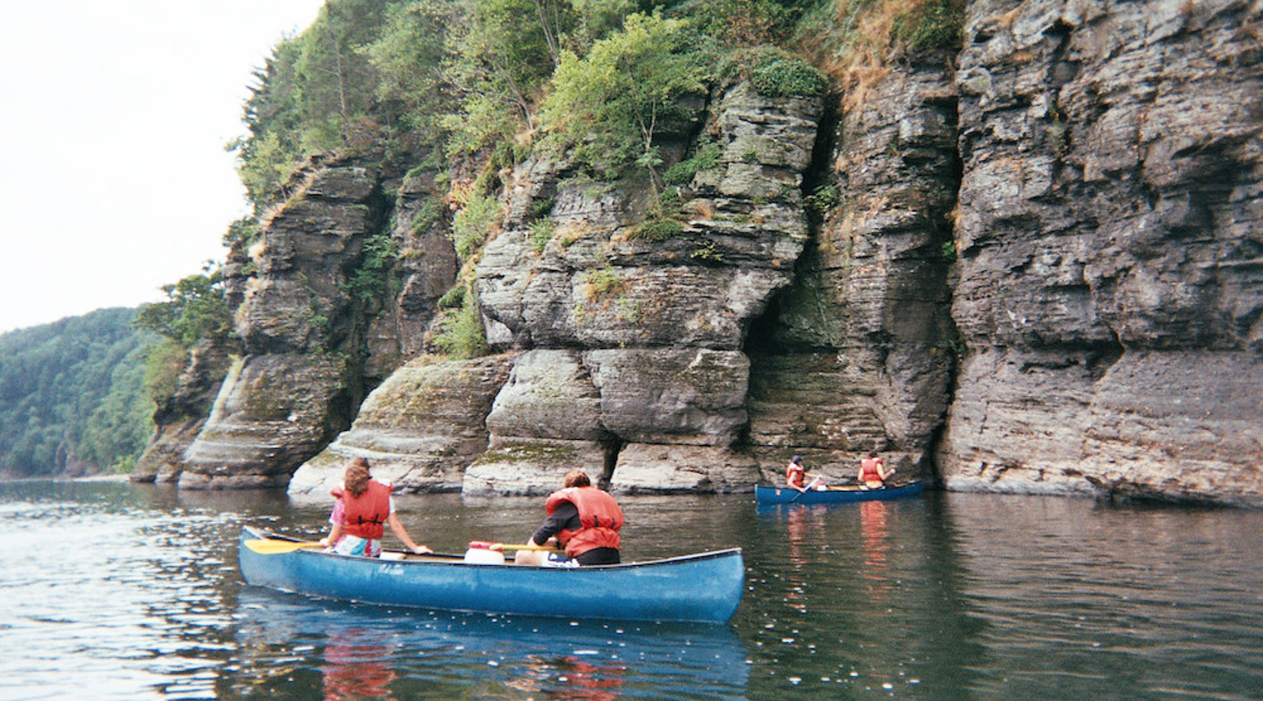 Campers in canoes by a cliff