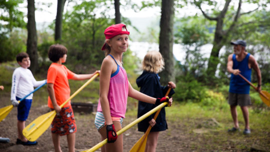 Campers practicing paddle techniques with canoe paddles