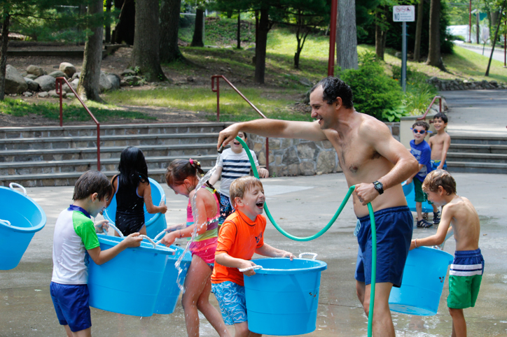 Counselor spraying campers with a hose